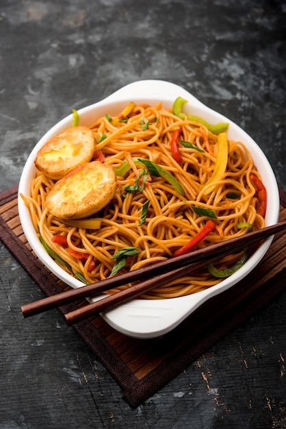 Nouilles hakka aux œufs Schezwanor, plats indochinois populaires servis dans un bol avec des baguettes. mise au point sélective