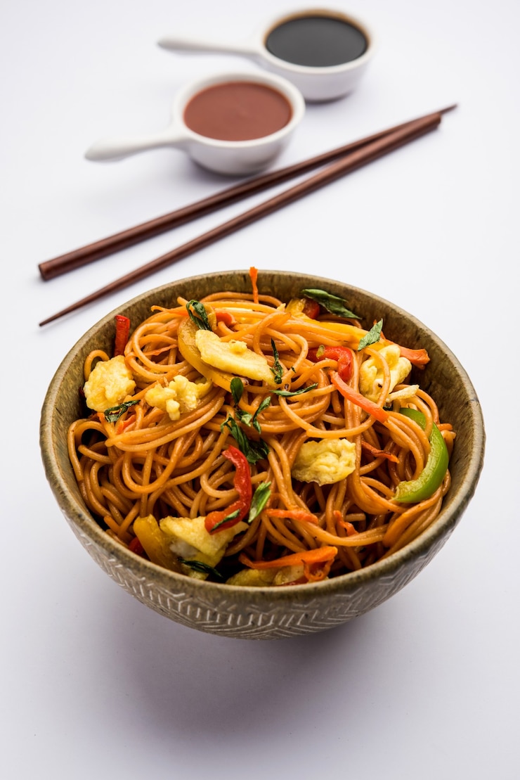 Photo nouilles hakka aux œufs schezwanor, plats indochinois populaires servis dans un bol avec des baguettes. mise au point sélective