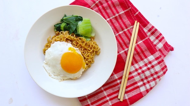 Photo nouilles instantanées servies avec des œufs frits et des légumes verts à la moutarde sur une assiette nouilles frites instantanées indomie