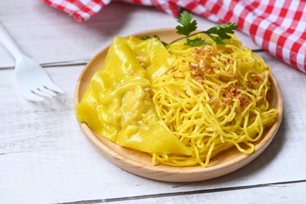 Nouilles jaunes sur plaque blanche et boulettes de porc fond en bois nouilles instantanées nouilles jaunes vermicelles de riz nourriture avec ail frit