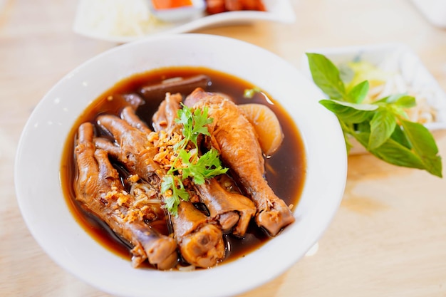 Photo nouilles de poulet braisées ou cuisse de poulet braisée dans un bol blanc sur la table du restaurant cuisine de rue thaïlandaise