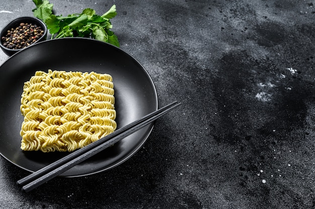 Nouilles ramen instantanées sèches et crues. Fond noir. Vue de dessus. Espace copie