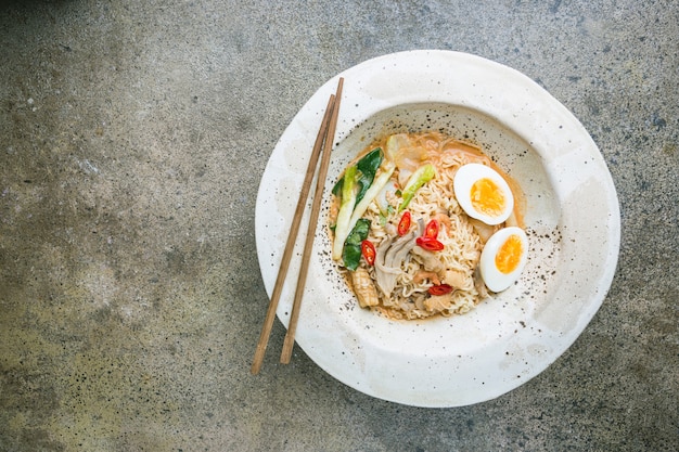 Nouilles ramen japonaises au poulet, champignons shiitake et œuf dans un bol blanc, vue de dessus