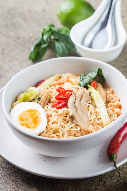 Nouilles ramen japonaises au poulet, champignons shiitake et œuf dans un bol blanc