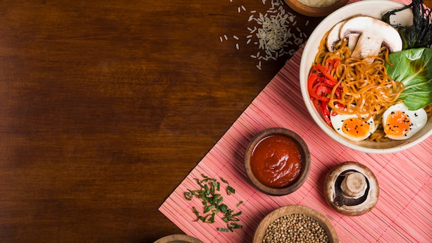 Nouilles Ramen de style asiatique avec des sauces sur une table en bois