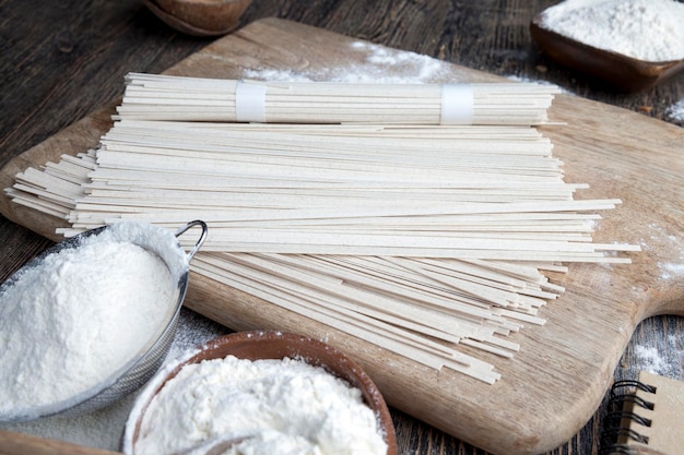 Nouilles de riz blanc et farine et autres ingrédients faisant cuire des nouilles de riz sur un gros plan de table en bois