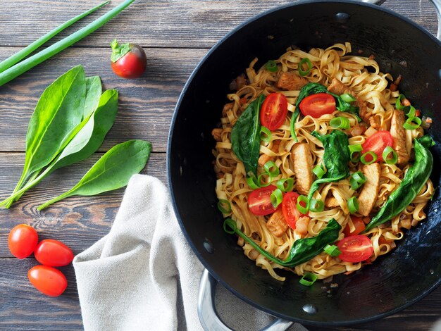 Photo nouilles sautées aux épinards frais et à la viande de dinde dans un wok en fer noir