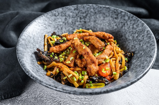 Nouilles sautées Udon avec viande de porc et légumes. Fond blanc.