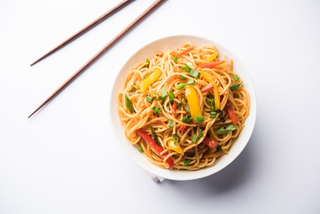 Les nouilles schezwan ou les nouilles hakka aux légumes ou chow mein sont des recettes indochinoises populaires, servies dans un bol ou une assiette avec des baguettes en bois