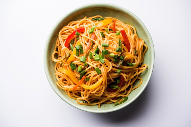 Les nouilles schezwan ou les nouilles hakka aux légumes ou chow mein sont des recettes indochinoises populaires, servies dans un bol ou une assiette avec des baguettes en bois