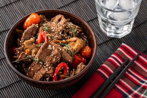 Nouilles soba au boeuf, champignons, tomates cerises et poivrons doux. Cuisine asiatique