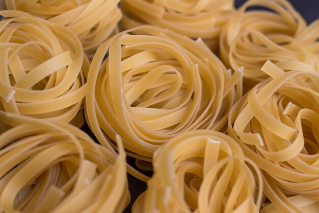 Photo des nouilles tagliatelle sur fond noir - gros plan