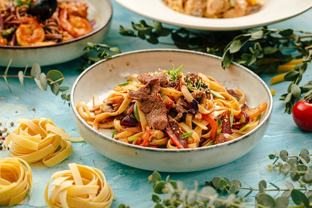 Nouilles udon frites avec de la viande de boeuf sur le fond bleu