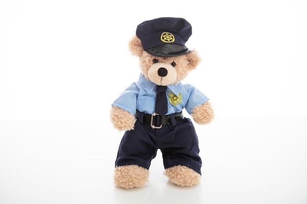 Nounours mignon en uniforme de policier isolé sur fond blanc