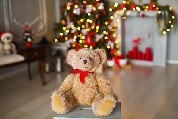 Nounours de Noël sur le fond d'une cheminée avec des bougies et un arbre de Noël