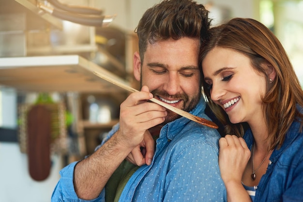 Nourrir leur mariage avec des aliments savoureux et nutritifs Photo d'un homme donnant à sa femme un avant-goût de la nourriture qu'il prépare à la maison