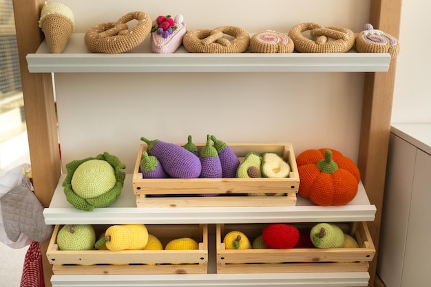 Nourriture artificielle dans la cuisine des enfants Sur l'étagère se trouvent des légumes et des fruits en fils tricotés