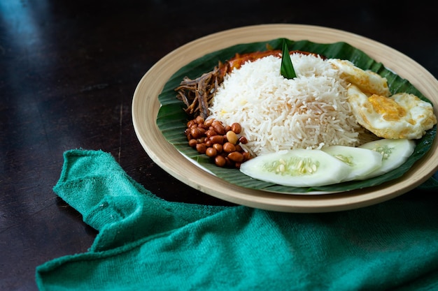 Photo nourriture asiatique traditionnelle de malaisie nasi lemak sur une feuille de banane dans une assiette en bambou en bois
