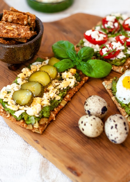 Nourriture biologique saine avec du pain grillé à l'avocat avec du fromage grec et du concombre et une petite brindille de basilic.