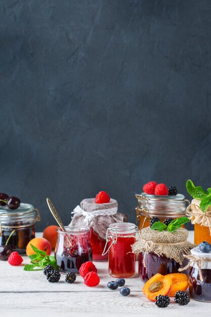 Nourriture et boisson, concept d'automne d'été de récolte. Assortiment de confitures de baies et de fruits de saison en pots sur une table en bois. Copiez l'arrière-plan rustique de l'espace