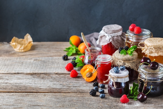 Nourriture et boisson, concept d'automne d'été de récolte. Assortiment de confitures de baies et de fruits de saison en pots sur une table en bois. Copiez l'arrière-plan rustique de l'espace