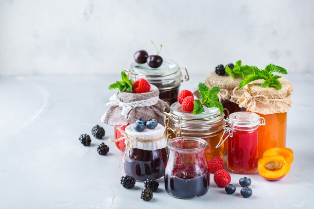 Nourriture et boisson, concept d'automne d'été de récolte. Assortiment de confitures de baies et de fruits de saison en pots sur une table en bois. Copiez l'arrière-plan rustique de l'espace