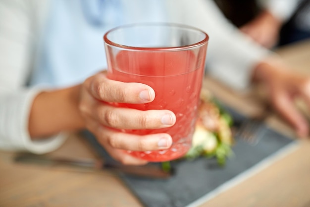 Nourriture, boisson, manger et concept de personnes - main de femme avec verre de jus et salade au restaurant