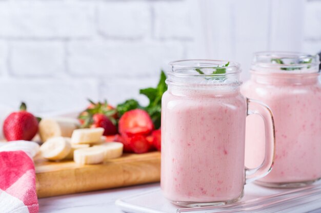 Nourriture et boisson, régime et nutrition sains, mode de vie, concept végétalien, alcalin, végétarien. Smoothie rose à la banane et à la fraise sur une table de cuisine moderne. Copier l'arrière-plan de l'espace