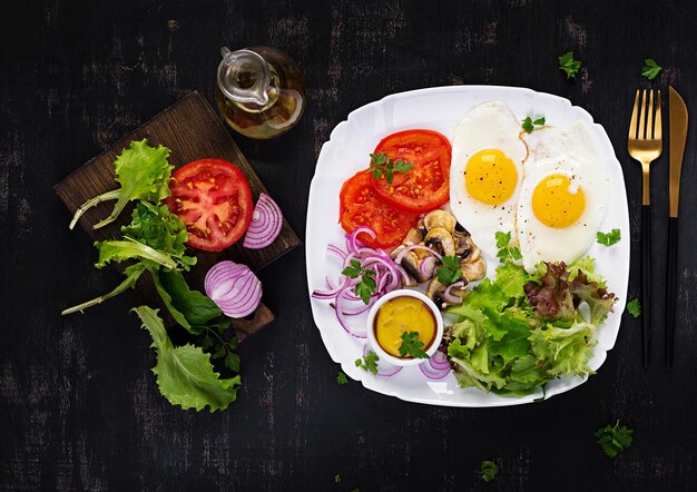 Nourriture cétogène Oeufs frits champignons et tomates en tranches Petit-déjeuner paléo Keto Vue de dessus espace de copie au-dessus