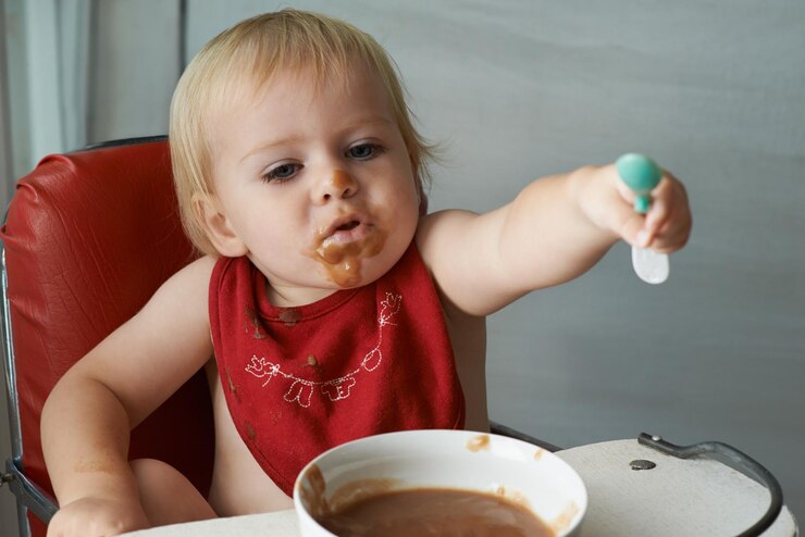 Photo nourriture chaise manger et bébé avec cuillère dans une maison pour la nourriture la nutrition et le plaisir tout en jouant la nourriture mangeur désordonné et garçon enfant à la maison avec le repas pour le développement de l'enfant régime alimentaire ou la nutrition tout en apprenant