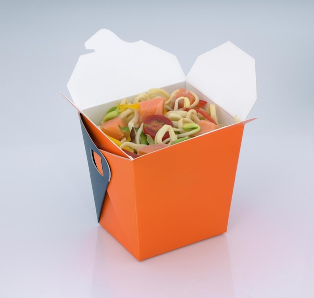 Nourriture chinoise aux nouilles à emporter avec de la viande et des légumes dans une boîte en carton sur fond clair