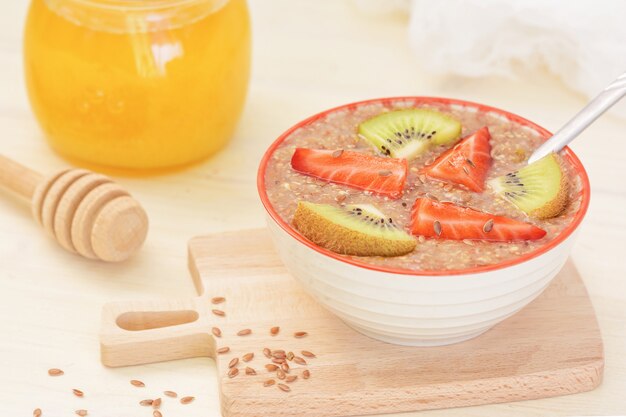 Nourriture crue, petit déjeuner végétalien. Bouillie de graines de lin avec du miel, des fraises et du kiwi.