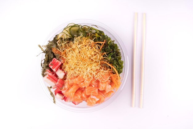 La nourriture japonaise orientale est poussée avec des baguettes et isolée sur un fond blanc.