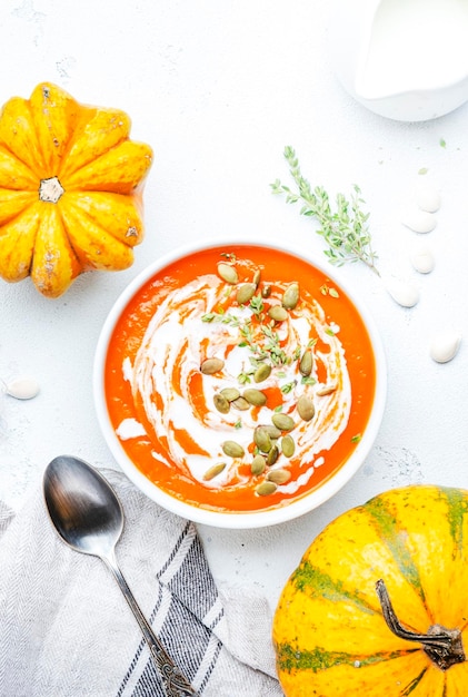 Photo nourriture lente d'hiver soupe de carottes à la citrouille avec des graines de crème et du thym alimentation saine bol de soupe blanc sur fond de table gris vue de dessus