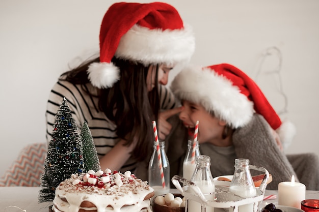 Photo nourriture de noël. une mère de famille heureuse et son fils s'embrassent et rient à la table des fêtes.