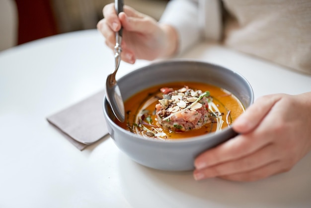 nourriture, nouvelle cuisine nordique et concept de personnes - femme mangeant des légumes soupe de crème de citrouille et de gingembre avec fromage de chèvre et salade de tomates avec yogourt dans un bol dans un café ou un restaurant