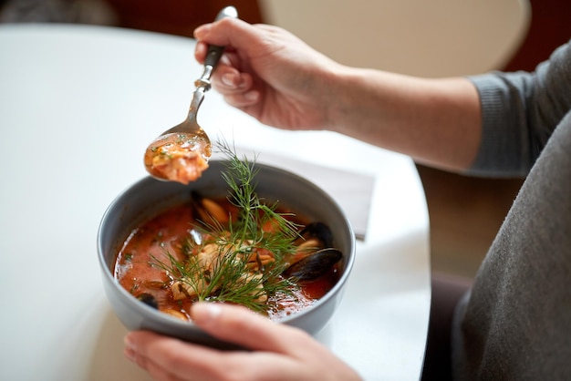 nourriture, nouvelle cuisine nordique et concept de personnes - femme mangeant une soupe de fruits de mer avec du poisson et des moules bleus dans un café ou un restaurant
