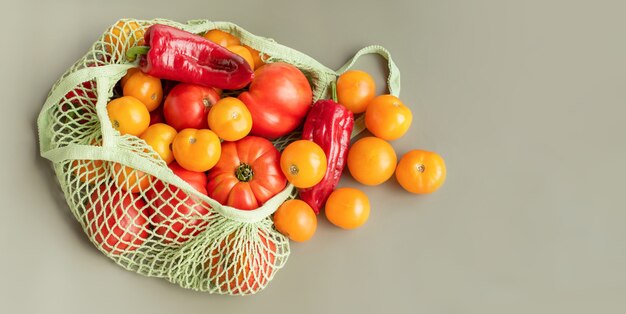 Nourriture en sac écologique vert. Légumes tomates et poivrons jaunes et rouges dans une grille.