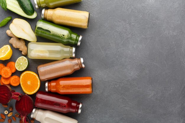 Nourriture saine. Assortiment de smoothies de désintoxication aux fruits et légumes dans des bouteilles en verre avec des ingrédients sur fond gris, espace pour copie, vue de dessus