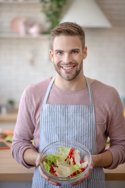 Nourriture saine. Un bel homme souriant tenant un bol de salade