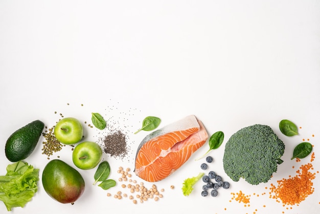 Nourriture saine comme le saumon, les légumineuses, les graines de chia, les légumes et les fruits sur fond blanc