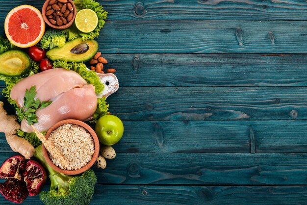 Nourriture saine Filet de poulet Avocat Brocoli Légumes frais Noix et fruits Sur un fond en bois Vue de dessus Espace de copie