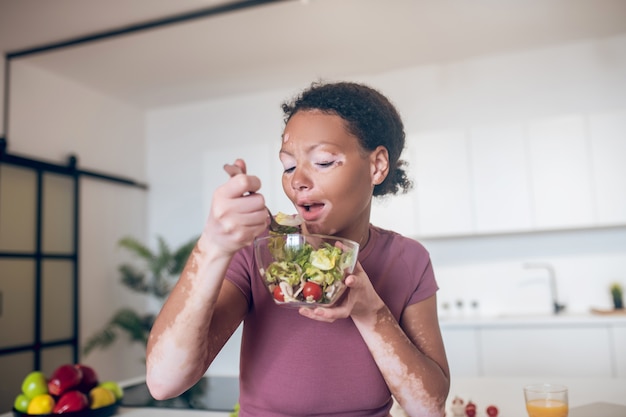 La nourriture saine. Une jeune femme avec une pigmentation sur son visage en train de manger de la salade