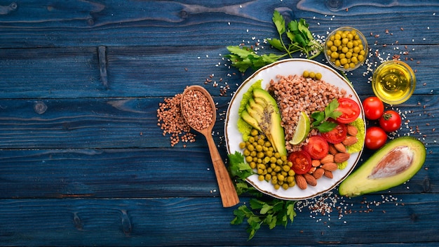 Nourriture saine Sarrasin tomates cerises avocats amandes et pois verts Sur un fond en bois Vue de dessus Espace libre pour votre texte