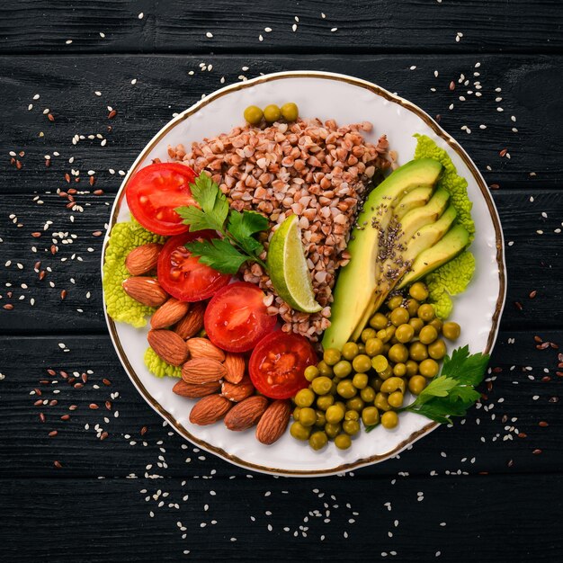 Nourriture saine Sarrasin tomates cerises avocats amandes et pois verts Sur un fond en bois Vue de dessus Espace libre pour votre texte