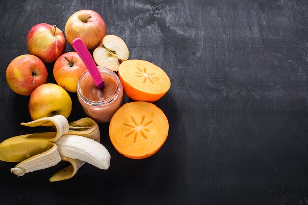 Nourriture saine. Yaourt aux fruits ou purée en verre avec différents fruits sur fond noir. Vue de dessus. Copier l'espace