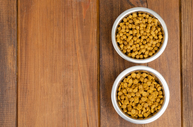 Nourriture sèche pour chat dans un bol en métal sur une surface en bois