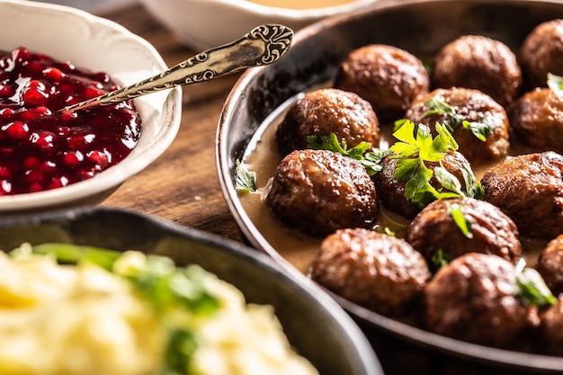 Photo nourriture suédoise boulettes de viande kottbullar, servies dans une poêle avec purée de pommes de terre, persil et sauce aux canneberges.