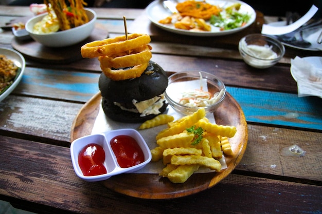 Photo la nourriture sur la table, un burger noir et des frites.