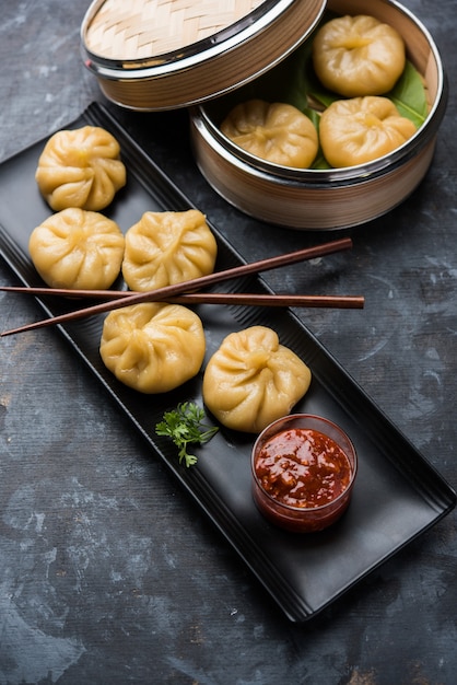 Nourriture traditionnelle de momos de boulette du Népal servie avec le chutney de tomate au-dessus du fond de mauvaise humeur. Mise au point sélective